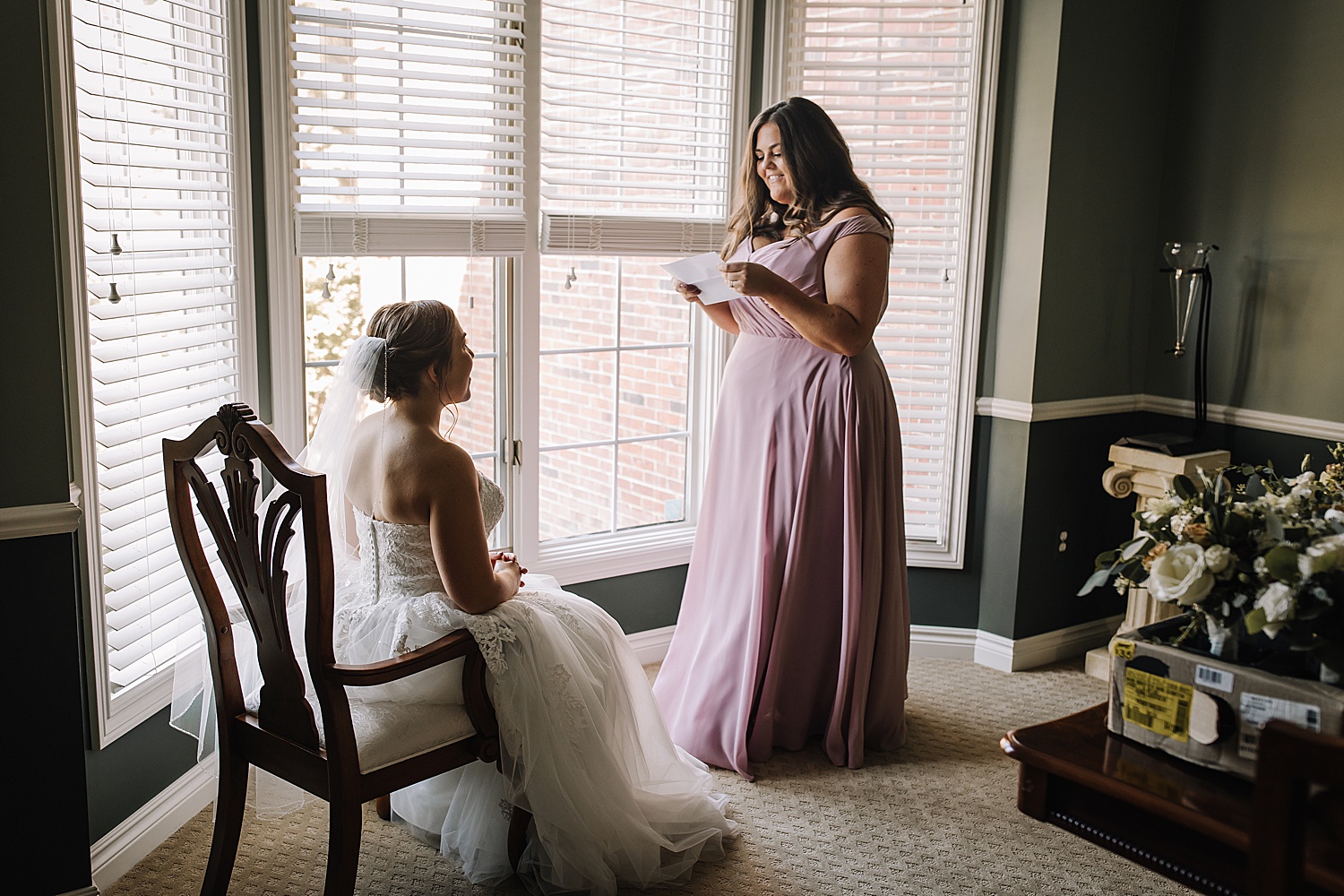 bridesmaid in long blush pink dress reading letter from groom to bride 
