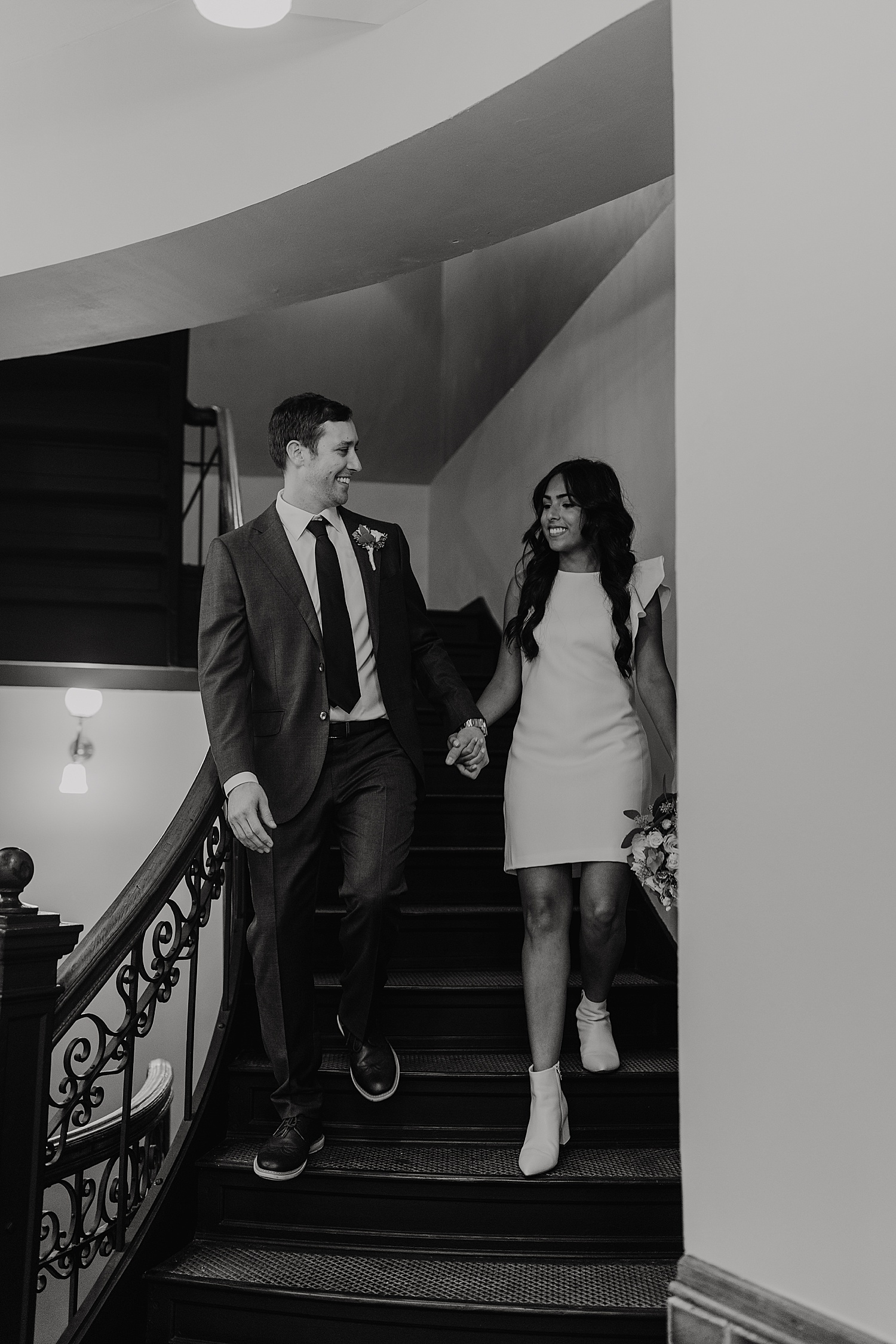 bride and groom holding hands while walking down the steps with Michigan wedding photographer 
