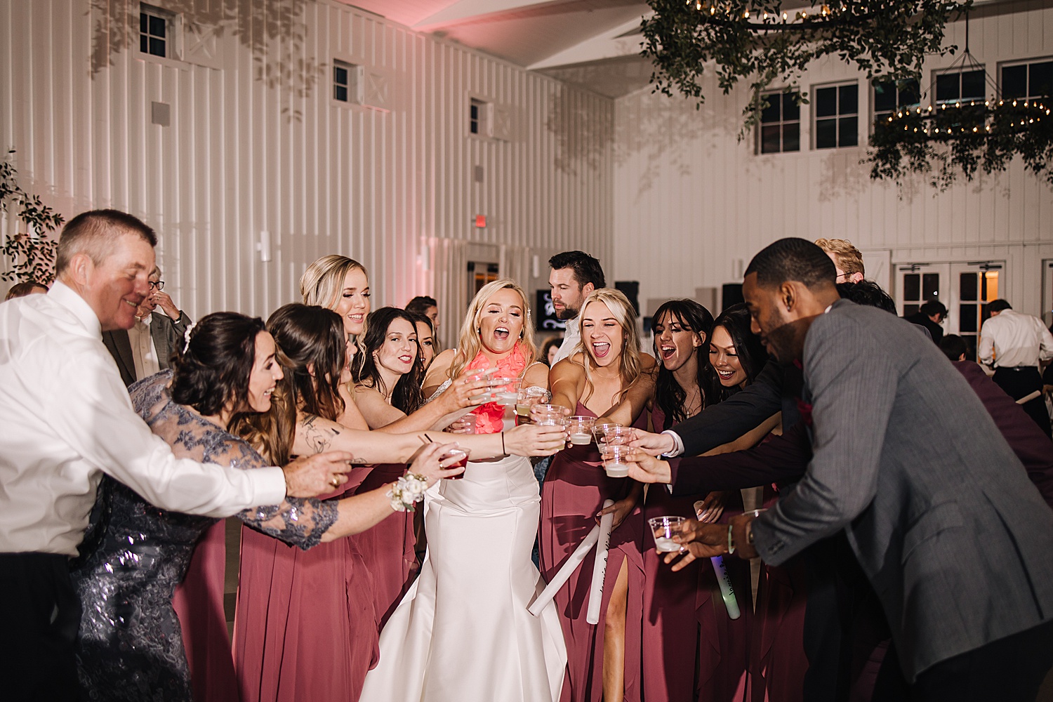 Bride and wedding guests take shots at the farmhouse wedding reception