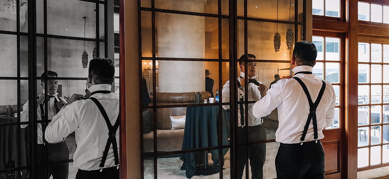 Groom getting ready in groomsmen suite with Floor to ceiling mirrors at the rice